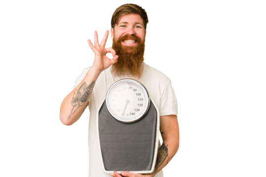 Adult redhead man with long beard holding a scale isolated cut out cheerful and confident showing ok gesture.