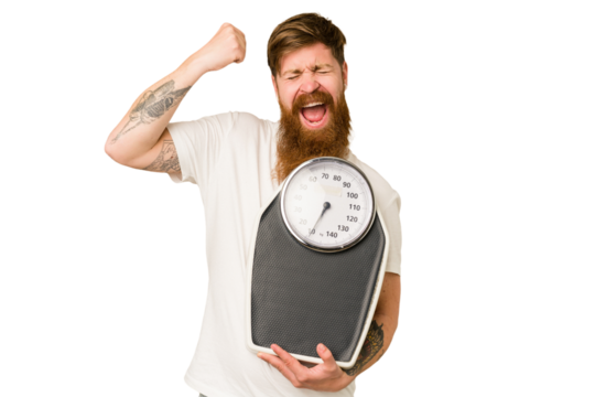 Adult redhead man with long beard holding a scale isolated cut out raising fist after a victory, winner concept.