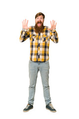 Young adult redhead man with a long beard standing full body isolated receiving a pleasant surprise, excited and raising hands.