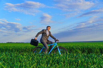 a businessman rides a bicycle with a briefcase on a green grassy field, dressed in a business suit, beautiful nature in spring, freelance business concept