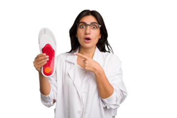 Young indian chiropodist woman holding a insoles for shoes cut out isolated pointing to the side