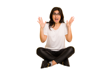 Young indian woman sitting on the floor cut out isolated celebrating a victory or success, he is surprised and shocked.