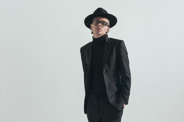 cool man with turtleneck and suit posing with hands in pockets