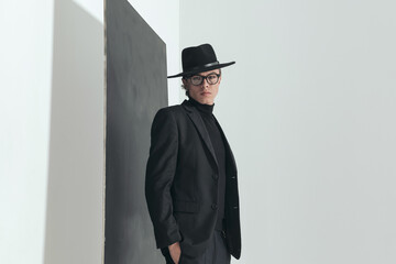 side view picture of elegant man with black suit posing with hands in pockets