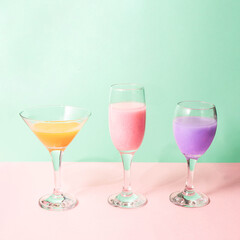Colorful cocktails on pastel light pink and green background. Creative drink concept. Minimalistic beverage composition.