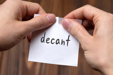 Hands of a man tearing a piece of paper with inscription decant