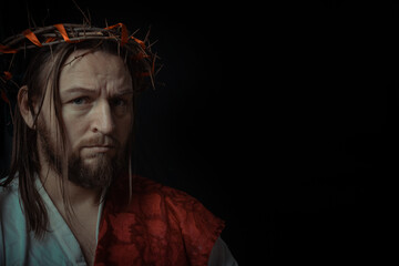 Fototapeta premium Jesus Christ wearing a crown of thorns and white chiton toga mantle cape himation suffering for mankind's sins in artistic mystical portrait