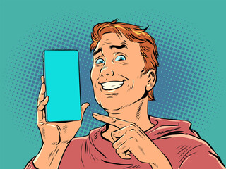 A man with red hair smiles and points to the phone. Product demonstration or offer on smartphone. The joy of a perfect purchase. Pop Art Retro