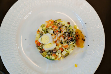 salad with shrimp and quail egg on a white round plate. Russian salad