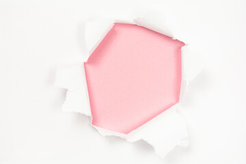 Torn white paper with hole on pink paper background, copy space