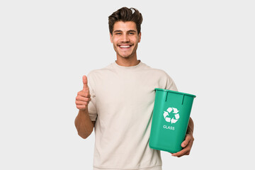 Young caucasian man holding a glass trash isolated smiling and raising thumb up