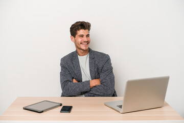Young entrepreneur man working with a laptop isolated smiling confident with crossed arms.