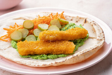 Fish fingers wraps with pea puree and vegetable in tortilla