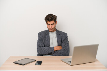 Young entrepreneur man working with a laptop isolated unhappy looking in camera with sarcastic expression.