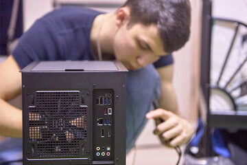Fototapeta na wymiar A young man, builds a new computer from components, cable management, the concept of assembling and repairing a computer