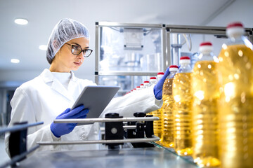 Food inspector or technologist taking good care of bottled vegetable oil inside bottling plant.