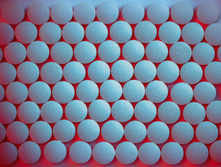Round blue pills on a flat surface - red shining background