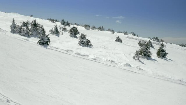 Aerial view of an athlete skies along snowy track on the ski slopes using technique of Telemark