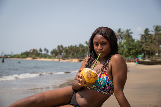 A young woman lying at the beach enjoying coconut milk, photo with copy space.