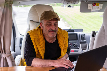 senior man using laptop in a motorhome, concept, digital nomad,