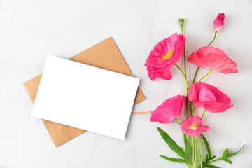 Blank greeting card with pink poppy flowers bouquet on white background. Wedding invitation. Mock up. Flat lay