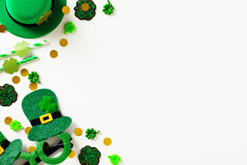 Happy St Patrick's Day greeting card template. Flat lay composition with leprechaun hat, confetti, party eyeglasses, decorations on white table.