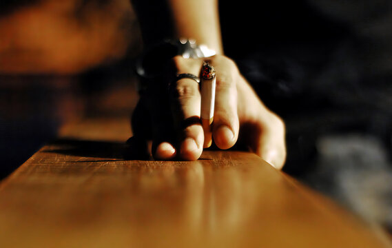 A hand holding a burning cigarette