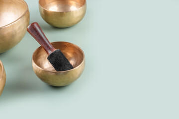 Tibetan singing bowls with stick used during mantra meditations on green background, top view, flat...