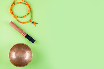 Tibetan singing bowl with stick, mala beads strands used during mantra meditations on green...