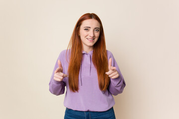 Young red hair woman isolated pointing to front with fingers.