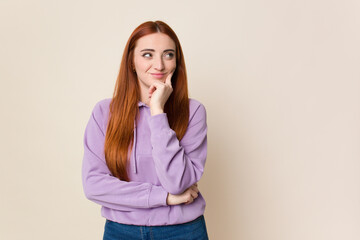 Young red hair woman isolated relaxed thinking about something looking at a copy space.