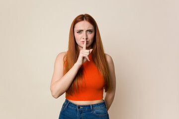 Young red hair woman isolated keeping a secret or asking for silence.