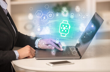 Hands working on laptop with digital icons