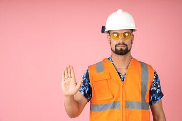 Serious man with reflective vest, helmet and safety glasses showing the palm of his hand