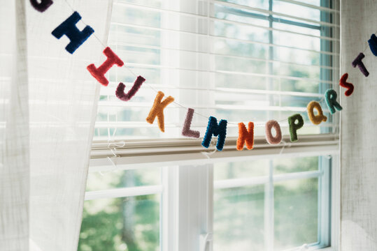 Multi colored alphabet decoration hanging on string by window at home