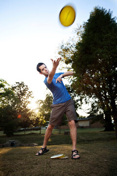 A man makes a forehanded drive playing disc golf. (Back Lit, Motion Blur)
