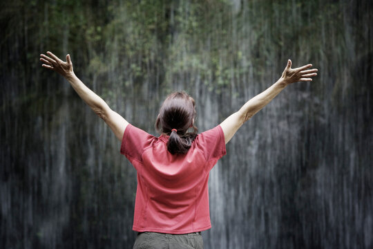 Rear view of woman standing in front of a waterfall.