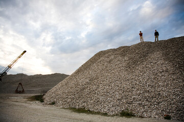 Two men stand atop a pile of oyster shells in Apalachicola, FL.