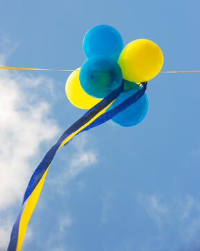 Blue and yellow balloons against a cloudy blue sky.