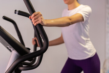 Fototapeta na wymiar Young sportswoman exercising on elliptical cross trainer