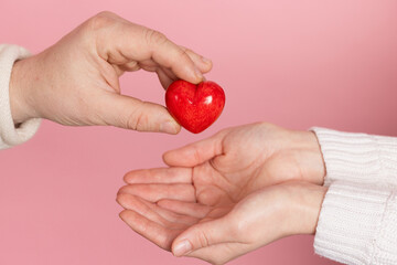 closeup hands holding heart on pink background, valentine's day concept