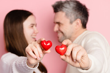 guy and girl holding heart together on pink background, valentine's day concept