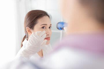 doctor use flashlight screening conjunctivitis patient, asian patient has red eyes and feeling...