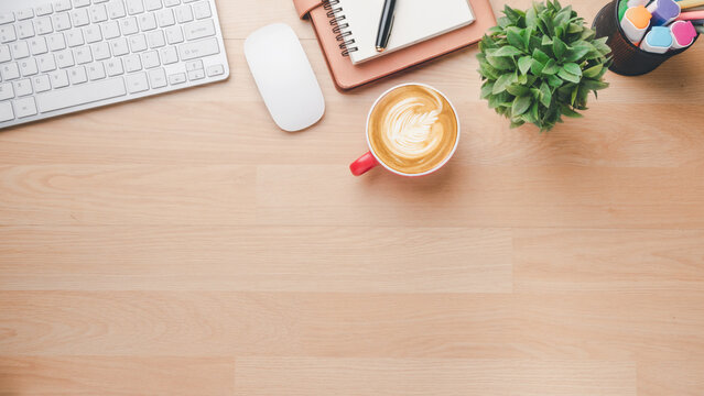 Office wooden desk workplace with keyboard, mouse, notebook, pen and cup of coffee, Top view flat lay with copy space.