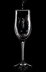 Water pours into a glass on a black background