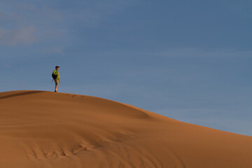 Fototapeta na wymiar A man looks out over the sand dunes at Coral Pink Sand Dunes State Park in Utah