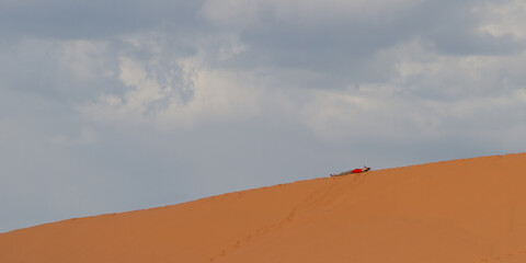 Fototapeta na wymiar A woman laying on a sand dune looking up at the sky