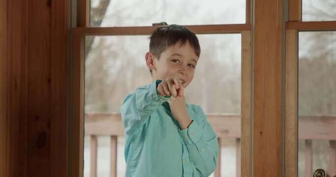 A Latino boy points and laughs hard at the viewer.