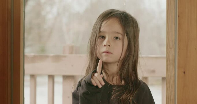 A small Latina girl wags her finger at someone to say 'no.'