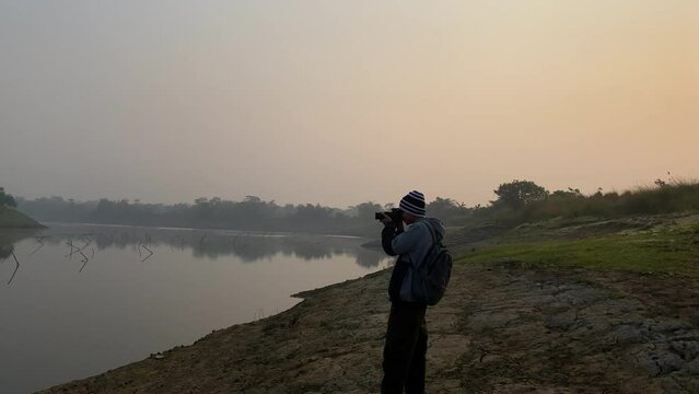 Young photographer with hat takes pictures of polluted river in Sylhet, dolly in